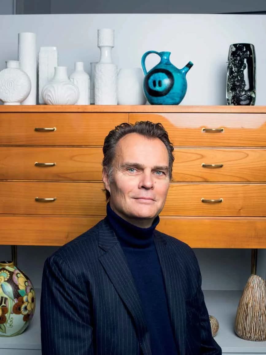 Portrait de Thibaut Wolvesperges, expert en œuvres d'art, devant une commode en bois et des céramiques.